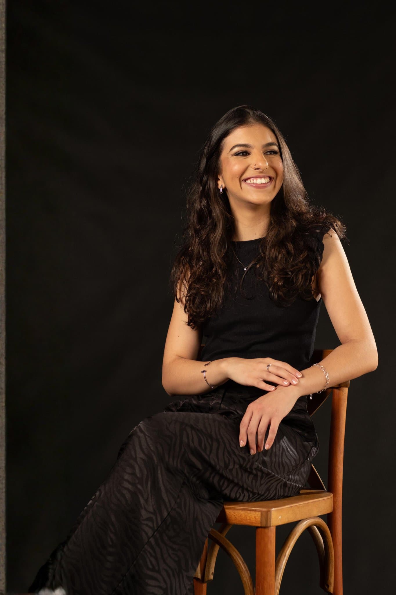Ana Carolina Calderaro sorrindo, sentada em uma cadeira de madeira